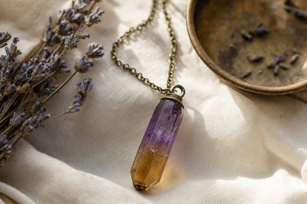 Ametrine crystal pendant necklace showing purple and golden bicolor zones styled with dried lavender