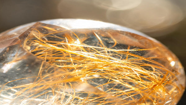 Rutilated quartz crystal with golden needle inclusions catching warm light