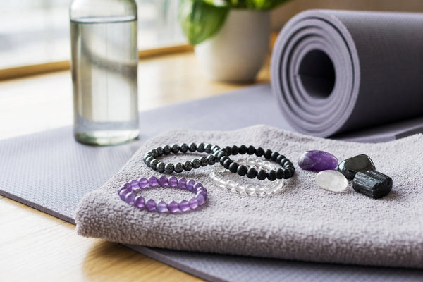Crystal bracelets and tumbled stones for post-workout recovery on a yoga mat