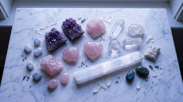 Healing crystals including amethyst, rose quartz, clear quartz, and selenite arranged on marble under moonlight