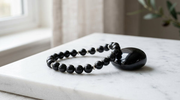 Black tourmaline bracelet with obsidian stone on marble surface